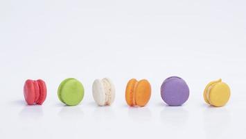 fila di mini macarons colorati su sfondo bianco foto