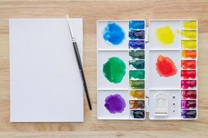 colori ad acquerello impostati in una tavolozza bianca con carta bianca per lo sfondo. foto