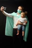 il padre con una maschera medica tiene la sua piccola figlia. il concetto di protezione dei bambini durante l'epidemia di coronavirus foto