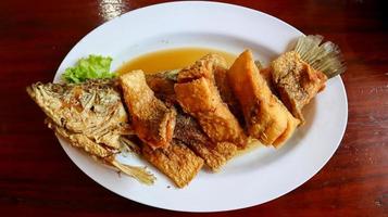 branzino fritto con salsa di pesce chiamato pla ga pong tod nam pla in tailandese. foto