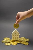 piccola casa modello bianca con criptovaluta bitcoin, mining di bitcoin e concetto finanziario foto