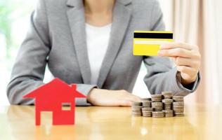 investimento immobiliare con carta di credito. casa e monete sul tavolo. foto