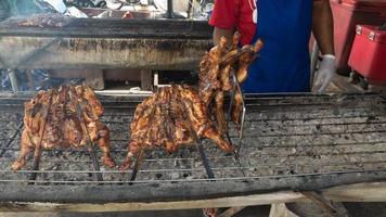 le persone stanno arrostendo il pollo in campagna su una semplice griglia, con movimenti sfocati nelle mani. foto