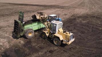 draga con rimorchio carico letame naturale per la concimazione in campo. macchina agricola per la concimazione. sterco di vacca foto