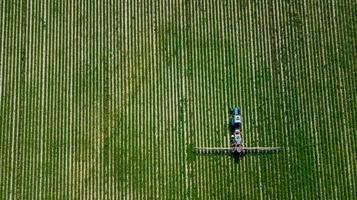 vista aerea dell'irroratrice agricola che lavora sul campo verde in una giornata di sole foto