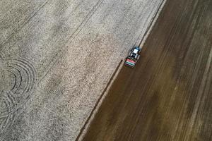 ripresa aerea dell'agricoltore con un trattore sulla semina del campo agricolo. trattori che lavorano nel campo agricolo in primavera. foto