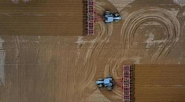 vista aerea dall'alto di un trattore, mietitrebbia che ara terreni agricoli in primavera foto