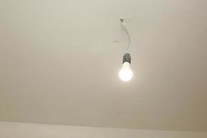 la lampadina sul soffitto bianco è accesa. riparazione foto