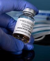 primo piano del flacone del nuovo vaccino covid-19 per la variante omicron con la mano guantata foto