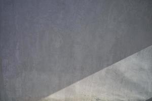 il muro di cemento presenta ombre e luce solare in diagonale. foto