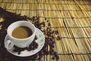 tazze di caffè e chicchi di caffè con fondo di bambù del cucchiaio di legno. copia spazio tono vintage. foto