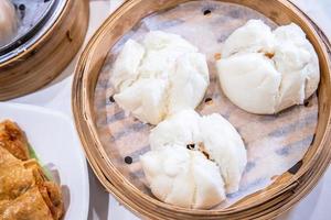 delizioso dim sum, famoso cibo cantonese in asia - cha siu bao fresco e caldo, panino di maiale barbecue in piroscafo di bambù nel ristorante yumcha di hong kong, primo piano foto