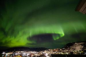 bella aurola luce del nord sopra il paesaggio urbano della città. aurora boreale nel sud di kitaa qaqortoq Groenlandia foto