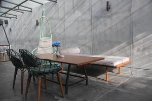 interior design per camera familiare con sfondo di muro di cemento, design industriale per la vita moderna, set di mobili, divano e sedie con tavolo e sedia sospesa in vimini. bandung, indonesia-, 2022 foto