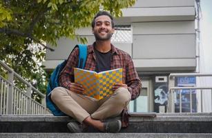 un ragazzo che legge il suo libro al campus universitario foto