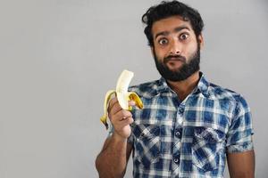 uomo che mangia banana e scioccato dalla conoscenza dei suoi benefici foto