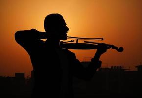 musicista che suona il violino. concetto di musica e tono musicale. immagini della siluetta dell'uomo musicista foto