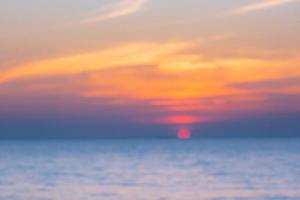 sfocato del tramonto colorato tropicale sull'oceano sulla spiaggia. al fondo del turismo della Tailandia con la spiaggia del mare. destinazione del viaggio di vacanza foto