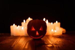 zucca di Halloween sullo sfondo di candele e uno sfondo nero. foto