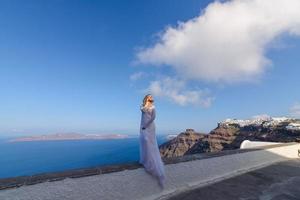 bella sposa in abito bianco in posa sullo sfondo del mar mediterraneo a thira, santorini. foto