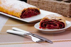 rotolo fatto in casa con marmellata su un piatto bianco con forchetta e coltello foto