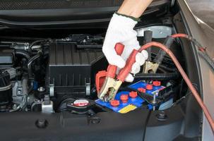 tecnico automobilistico che carica la batteria del veicolo foto