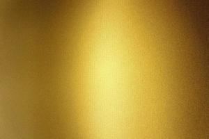 luce che brilla sulla parete in lamina metallica dorata, sfondo a trama astratta foto