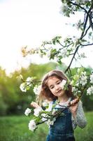 una graziosa bambina di 5 anni in un frutteto di mele bianco in fiore in primavera. primavera, frutteto, fioritura, allergia, profumo di primavera, tenerezza, cura della natura. ritratto foto