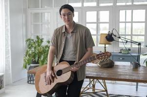 ritratto di un musicista uomo che tiene la chitarra in studio domestico foto