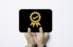 mano che tiene una carta nera con garanzia di qualità dorata e segno del certificato di garanzia. foto