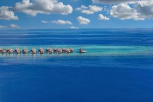 scenario paradisiaco delle maldive. paesaggio aereo tropicale, paesaggio marino con lungo molo, ville sull'acqua con splendida spiaggia di mare e laguna, natura tropicale. banner di destinazione turistica esotica, vacanze estive foto