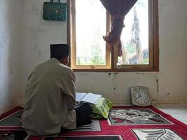 reggenza di cianjur, indonesia, 3-30-22-uomo che legge il Corano in una stanza foto