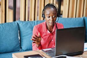 donna afroamericana lavora in un operatore di call center e agente del servizio clienti che indossa cuffie con microfono che lavorano su laptop. foto