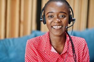 donna afroamericana lavora in un operatore di call center e agente del servizio clienti che indossa cuffie con microfono che lavorano su laptop. foto