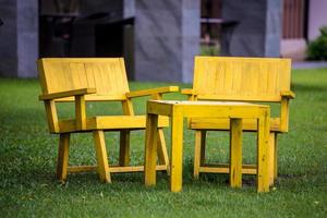 un paio di sedie di legno gialle senza nessuno si siedano su di esso nel giardino all'aperto. foto