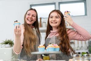 felice madre e figlia orgogliosa di mostrare la torta fatta in casa. il tempo in famiglia godetevi la cottura di prodotti da forno in cucina insieme durante il fine settimana foto