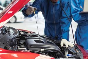 meccanico di automobile che controlla il livello dell'olio nel motore dell'auto presso il negozio di garage automatico. dopo il concetto di servizio di riparazione foto