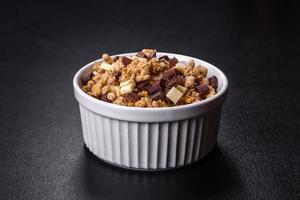 gustosa colazione sana con cereali, muesli, cioccolato, latte e marmellata su uno sfondo di cemento scuro foto