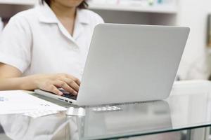 farmacista con computer portatile e farmaci in farmacia foto