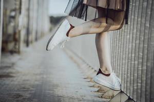 gambe ragazza adolescente in scarpe da ginnastica bianche sul ponte. foto