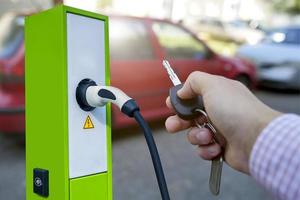 l'auto elettrica si sta ricaricando dalla stazione di ricarica nel parcheggio. concetto di fonti di energia alternative nell'industria automobilistica. risparmiare energia. potere verde. foto