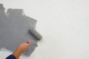 dipingere le pareti con un rullo nella mano sinistra. foto