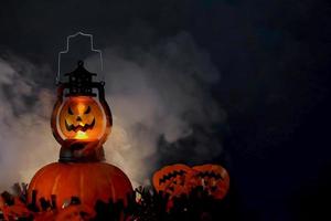 concetto di sfondo scuro di halloween con lanterna incandescente e zucche con fumo foto