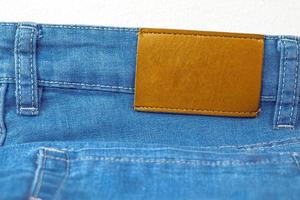 pelle brillante vuota sul retro dei jeans blu, etichetta marrone sulla cintura dei jeans per indossare lettere, sfondi in denim etichetta vestiti in vendita, etichette etichetta pantaloni nuovi di zecca, foto