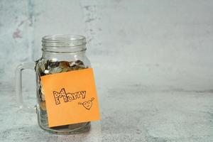 concetto per risparmiare denaro per il matrimonio, carta da lettere su salvadanaio, bottiglia di vetro con moneta foto