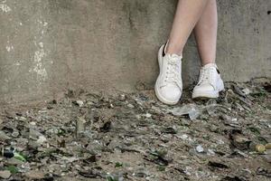 i piedi di un adolescente in un mucchio di vetri rotti e detriti. adolescenti in difficoltà e tossicodipendenza foto