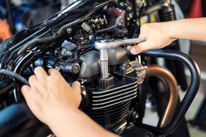 meccanico che utilizza una chiave inglese e una presa sulla testata di una motocicletta .manutenzione, riparazione moto concetto in garage .messa a fuoco selettiva foto