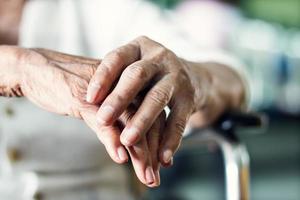 mani ravvicinate della paziente anziana anziana che soffre del sintomo della malattia di pakinson. concetto di salute mentale e assistenza agli anziani foto