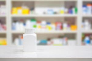 bottiglia di medicina bianca vuota sul bancone con scaffali sfocati di droga nella farmacia farmacia foto
