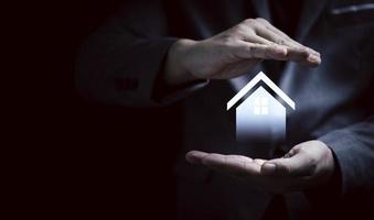 mano dell'uomo d'affari che protegge la casa virtuale per il concetto di assicurazione sulla proprietà immobiliare. foto